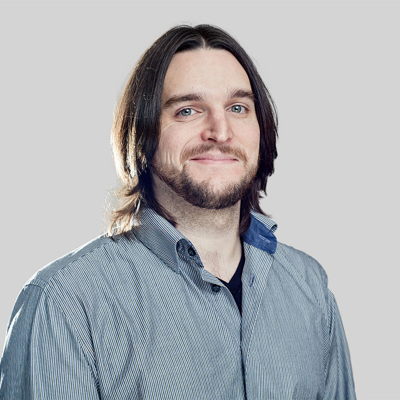 A man with long hair and beard wearing a blue shirt.