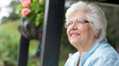 A woman with glasses sitting outside smiling.