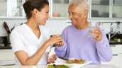 A woman and an older man are eating food.