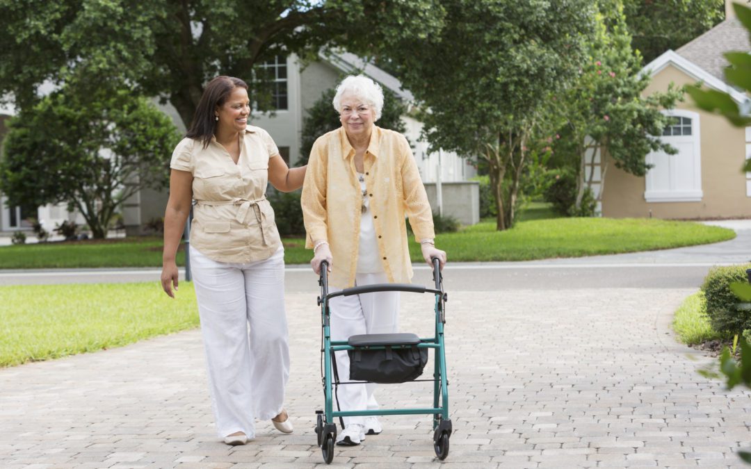 A woman pushing an older lady in a walker.