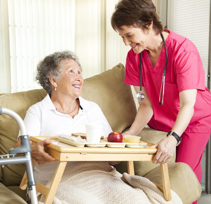 A nurse and an elderly woman sitting on a couch.