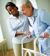 A woman helping an older man use a walker.
