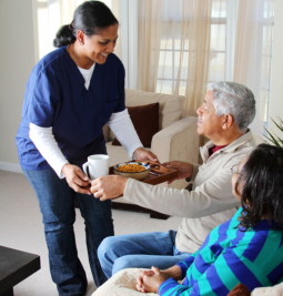 A woman handing food to an elderly man.