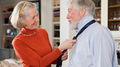 A woman adjusting the neck tie of an older man.