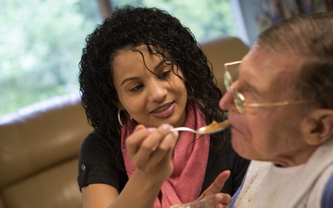 A woman feeding a man with a spoon.