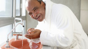A man smiles while holding his teeth.