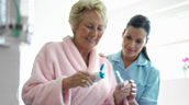 A woman and her nurse are brushing their teeth.