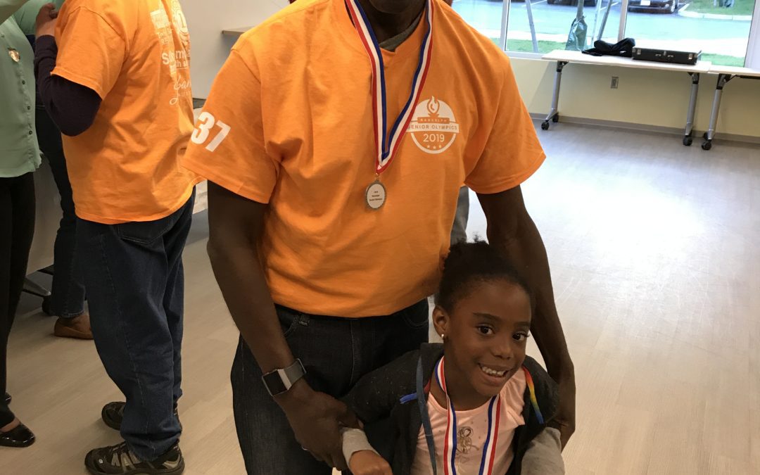 A man and child holding medals in front of an audience.