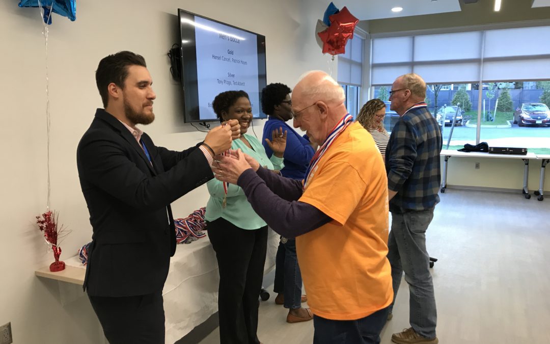 A man giving medal to an old man