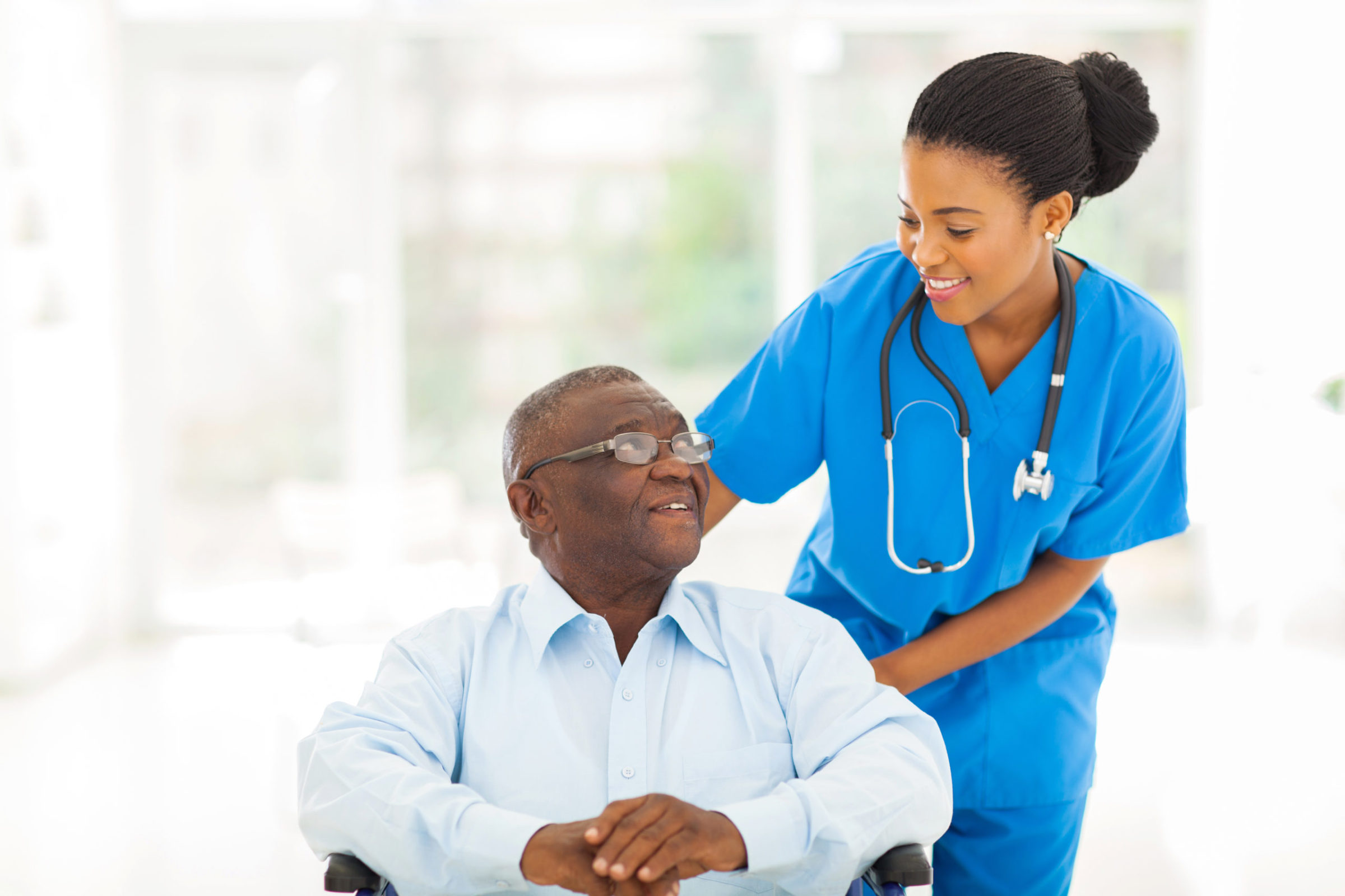 A nurse is helping an elderly man in a wheelchair.