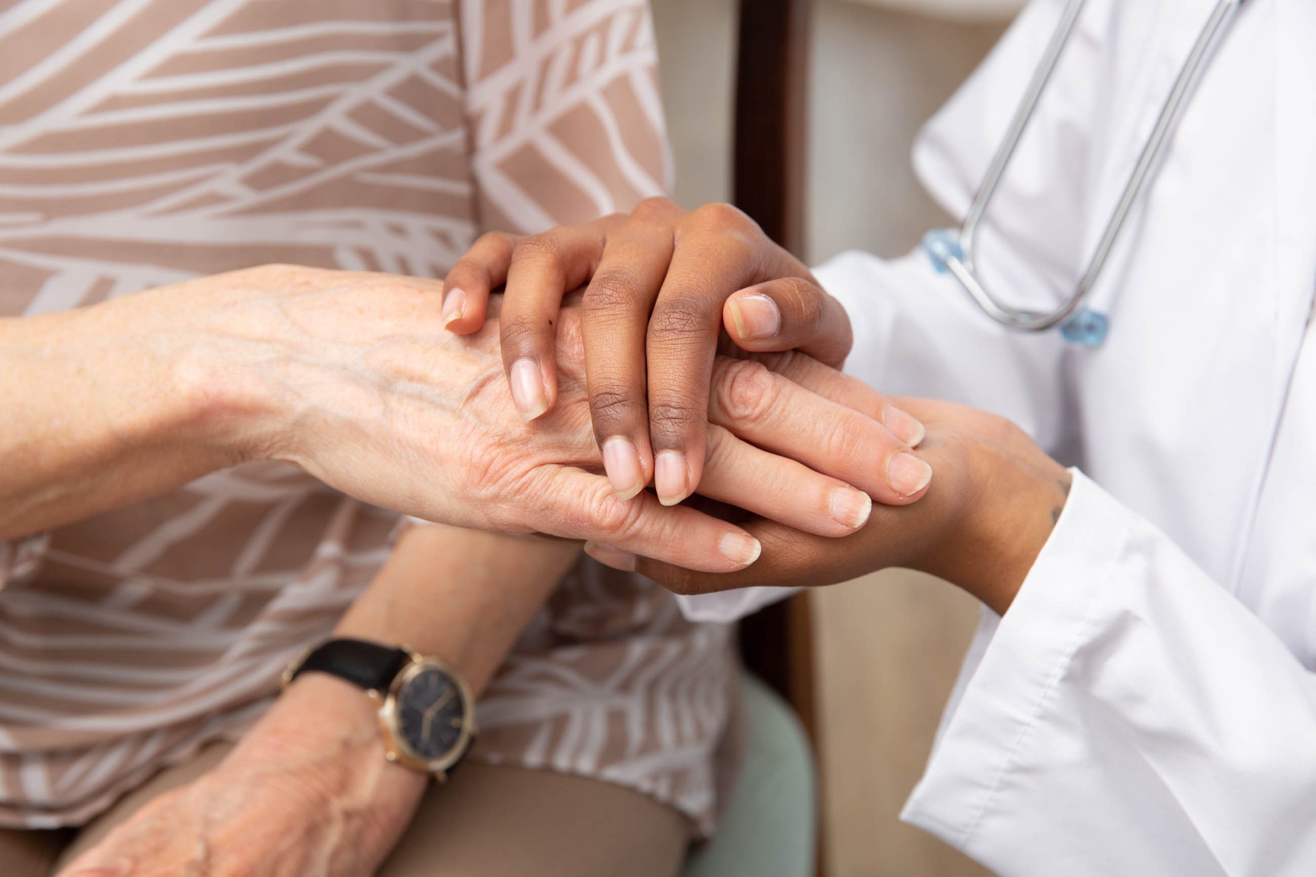 A doctor and patient holding hands in a room.