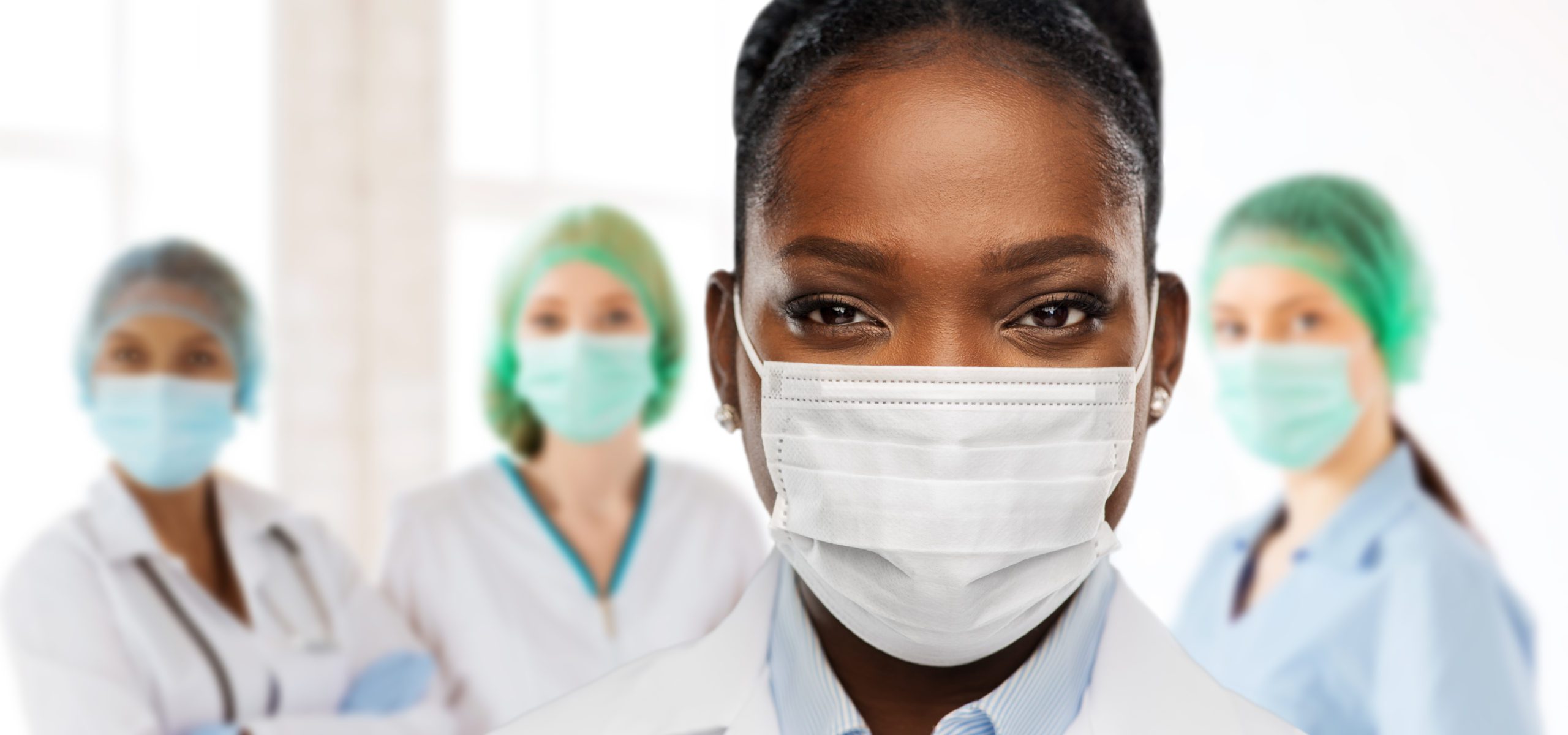 Two doctors wearing masks and standing in a room.