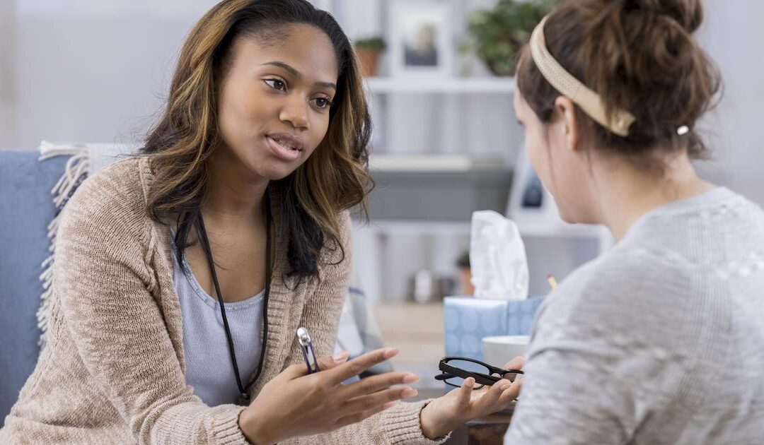 A woman talking to another person in front of a table.